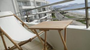 a table and chair on a balcony with a view of the beach at La Serena Departamento vista al mar in La Serena