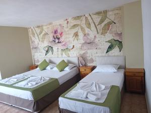 two beds in a room with a wall with flowers at Family Hotel Sofi in Sozopol +119 photos