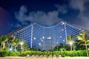 a large building with palm trees in front of it at Holi Arena Cam Ranh Seaview Premier Apartment in Thôn Hòa Ða