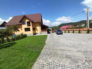 a house with a car parked next to a driveway at Pensiunea Teona in Târgu Ocna