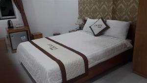 a bedroom with a bed with white sheets and pillows at Motel Sơn Hoa in Da Nang