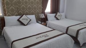 two beds in a hotel room with white sheets at Motel Sơn Hoa in Da Nang