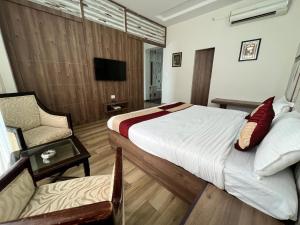 a bedroom with a bed and a chair and a television at Rudraksh Resort and Hotel in Rewāri