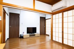 a living room with a television and sliding glass doors at SunRise STAY Atami Ajiro in Ajiro