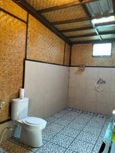 a bathroom with a toilet and a tiled floor at Tangga Bungalows Gili Air in Gili Air