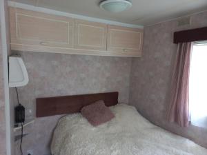 a small bedroom with a bed in the corner at Przyczepa holenderska in Ińsko