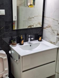 ein Badezimmer mit einem weißen Waschbecken und einem Spiegel in der Unterkunft Apartman Porto in Tivat