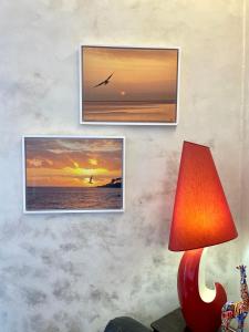 a wall with two pictures of the ocean and a lamp at Les Remparts Antibes Location in Antibes