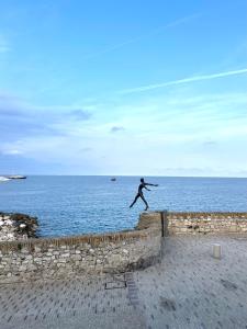 a man is jumping off a wall near the ocean at Les Remparts Antibes Location in Antibes