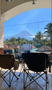 two chairs on a patio with a view of a mountain at HARMONI GUEST HOUSE tumpak sewu in Sumberbopong