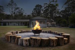 a fire pit with wooden logs around it at 'Avondale' Luxe Country Retreat in Pitt Town