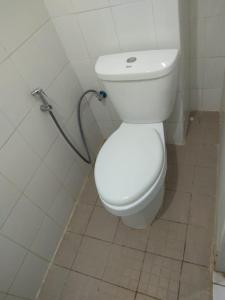 a white toilet in a bathroom with a hose at Dramaga Tower Apartemen by Rendy Roomme in Bubulak 3