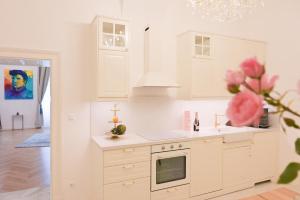 a kitchen with white cabinets and a vase of flowers at Villa Gutenberg Le Grand in Klagenfurt