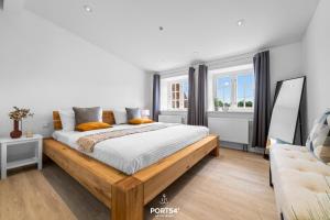 1 Schlafzimmer mit einem Holzbett und 2 Fenstern in der Unterkunft Ferienhaus Loft an der Ostsee Glücksburg in Glücksburg