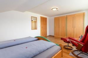 una camera da letto con due letti e una sedia rossa di Wallgauer Hof a Wallgau