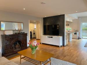 a living room with a fireplace and a table with flowers at Modern villa i Sävedalen in Gothenburg