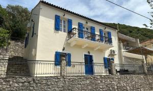 a white house with blue windows and a balcony at Spilia Apartments in Stavros