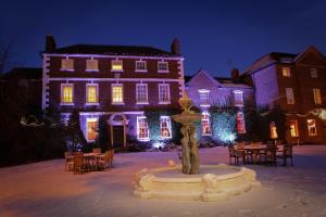 uma casa com uma fonte em frente com luzes de Natal em Park House Hotel em Shifnal