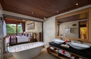 a bathroom with two sinks and a tub and a bedroom at Pita Maha Resort & Spa in Ubud