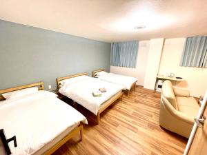 a hotel room with two beds and a chair at Little Garden in Otaru