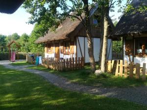 a house with a thatch roof and a fence at Zagroda Pod Gontem in Kopalino