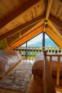 a attic bedroom with two beds and a large window at VAESS Villa Dağ Evleri in Çamlıhemşin