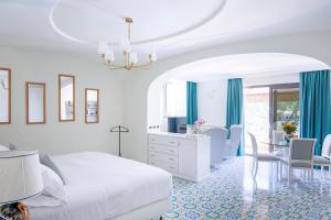 biała sypialnia z łóżkiem, biurkiem i krzesłami w obiekcie La Reginella Resort & Spa w mieście Ischia