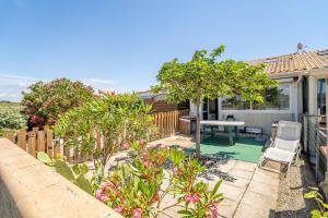 een achtertuin met een tafel en stoelen en een hek bij Les Eaux Vives 1 in Fleury