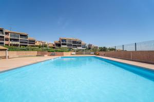a large blue swimming pool with buildings in the background at Les Eaux Vives 1 in Fleury