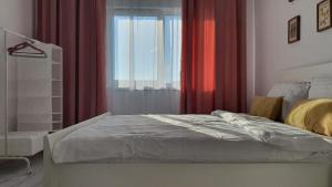 a bedroom with a bed and a window with red curtains at La Ana Apartament in Şelimbăr
