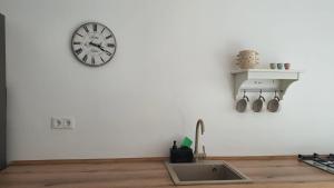 a clock on the wall above a kitchen sink at La Ana Apartament in Şelimbăr +19 photos