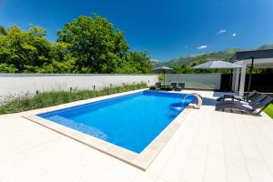 a swimming pool with two chairs and an umbrella at Holiday Home Noa in Mostar