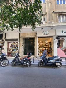 dos motocicletas estacionadas frente a una tienda en Paradise+ With Jacuzzi In the heart of Athens!, en Atenas