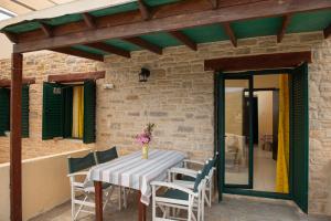 a patio with a table and chairs and a brick wall at Apartments and Studios Xenophon in Matala