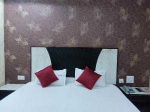 a bedroom with a white bed with red pillows at Hotel Ambassador Inn in Gwalior