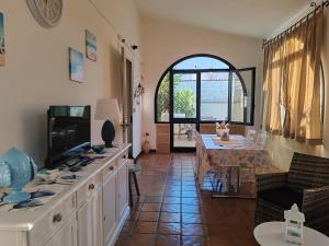 a living room with a television and a dining table at A L' ARIA FRISCA - villetta a due passi dal mare in Torre Lapillo