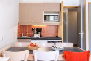 a kitchen with a table and chairs and a kitchen with a counter at Résidence Pierre & Vacances Le Machu Pichu in Val Thorens