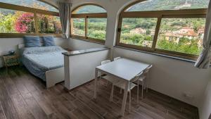 a bedroom with a bed and a table and windows at Al Beo in Finale Ligure