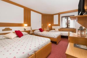a hotel room with two beds and a television at Hotel Bellavista in Pinzolo