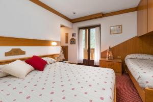 a bedroom with two beds and a window at Hotel Bellavista in Pinzolo