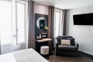 a bedroom with a bed and a chair and a mirror at Hotel de la Paix Tour Eiffel in Paris