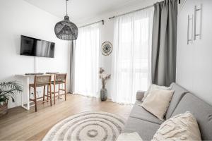 a living room with a gray couch and a kitchen at Bali style apartment with balcony near Gates of Dawn in Vilnius