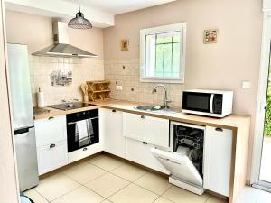 a kitchen with white cabinets and a sink and a microwave at Chez Coccinelle in Marmagne