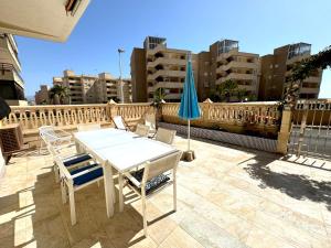 a table and chairs and an umbrella on a balcony at Casa en la playa de los Arenales in Arenales del Sol