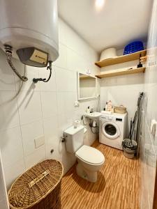 a bathroom with a toilet and a washing machine at Casa en la playa de los Arenales in Arenales del Sol
