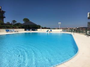 a large blue swimming pool with chairs and a gazebo at APPARTEMENT PISCINE TERRASSE 1 MIN PLAGE et GOLF in Bidart +14 photos