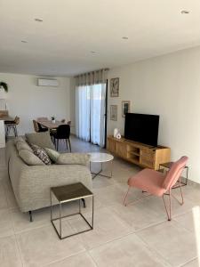 un soggiorno con divano e TV a schermo piatto di La Maison Louis - moderne & familiale a Lapalme