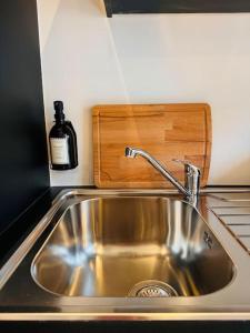 a stainless steel sink in a kitchen with a bottle of wine at Urbanchic Opéra 2B in Liège