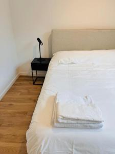 a bed with white sheets and a lamp on a table at Urbanchic Opéra 2B in Liège