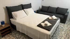 a bedroom with a bed with two pillows and a couch at R&B Apartments in Budva